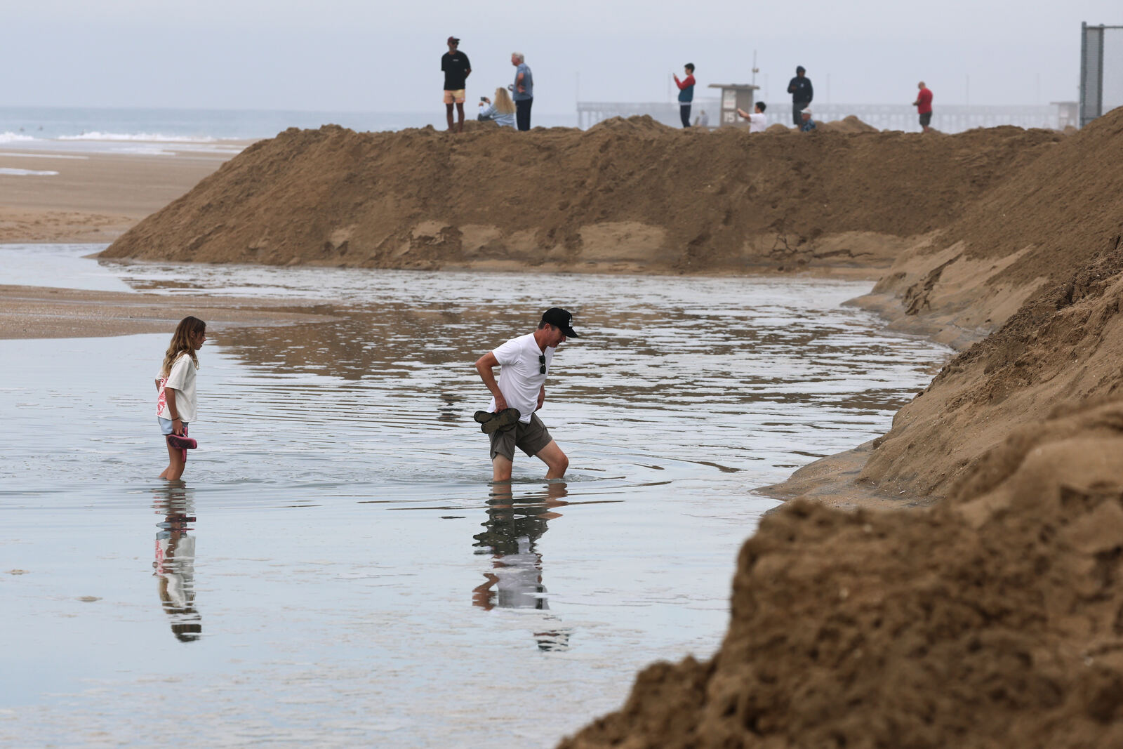 10月10日 Newport Beach 海滩沙堤后的积水中，Costa Mesa 一对父女涉水而过（Allen J. Schaben / Los Angeles Times）